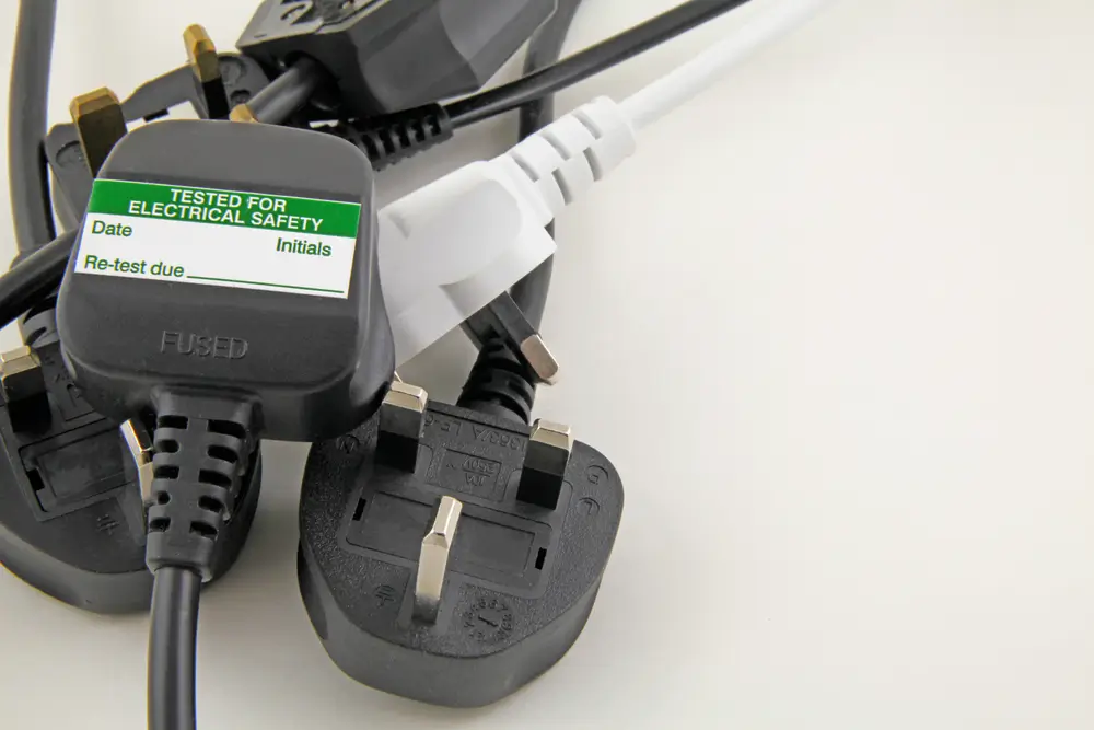 Electrical plug with a portable appliance testing safety label attached.