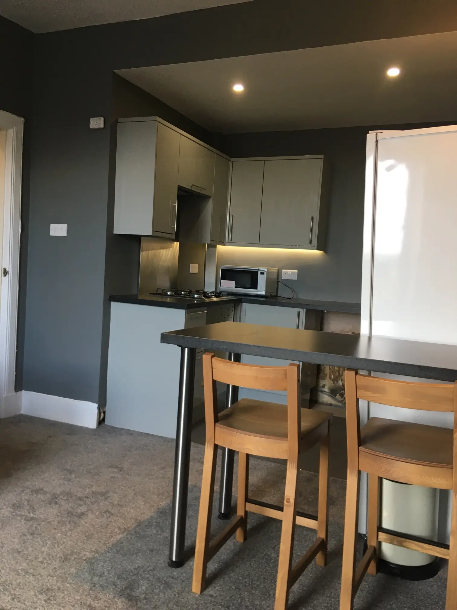 After restoration: the kitchen with pale cabinets, a fridge-freezer and a breakfast bar open to the living area.